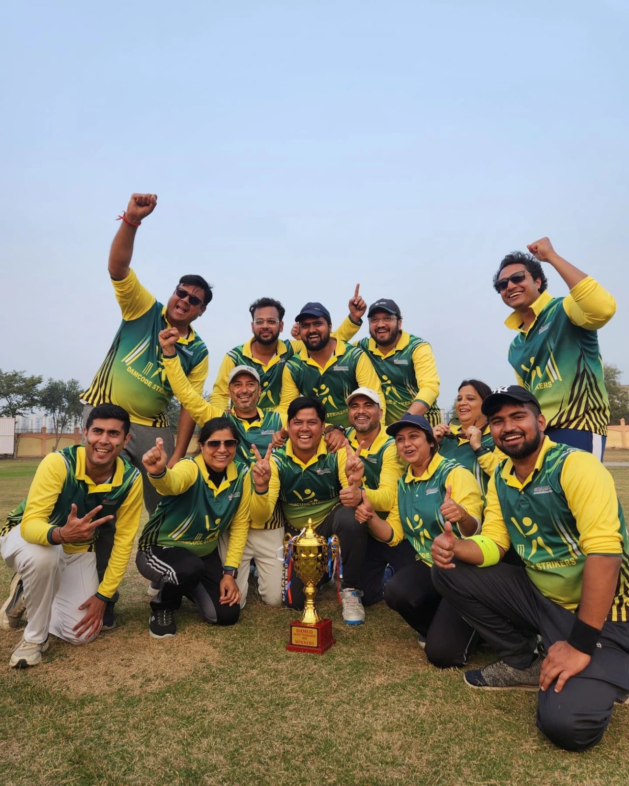A Damco cricket team cheering with their trophy