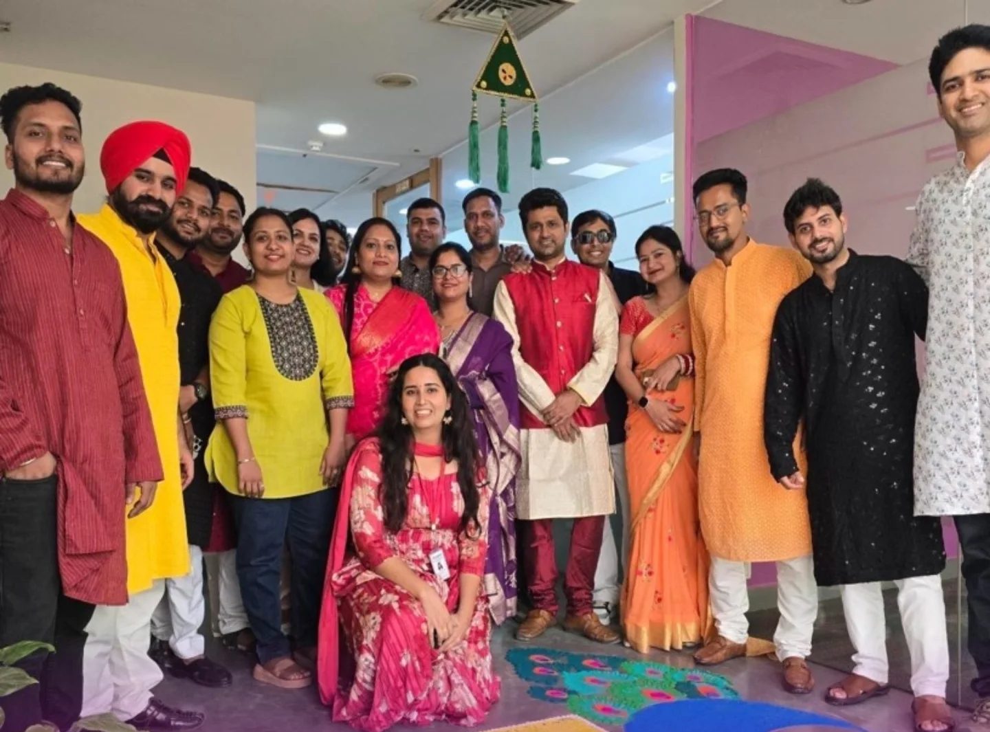 Colleagues in festive dress around a rangoli at Damco's Diwali celebration
