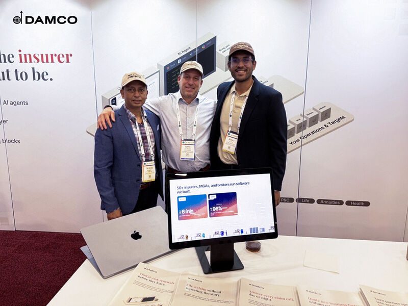 Damco's insurance team beside a demo screen at their booth